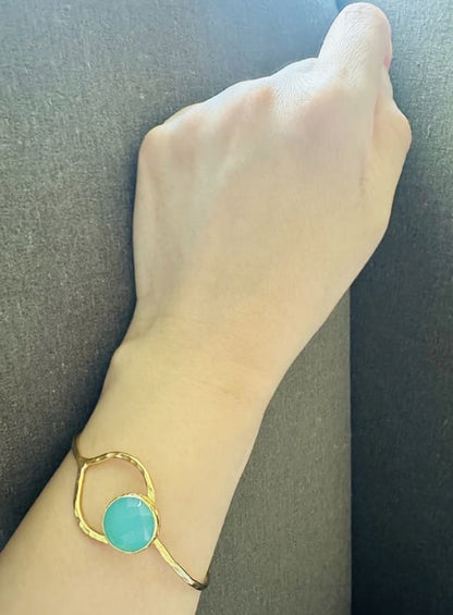 Gold-plated Aqua chalcedony bracelet on a wrist against a dark background