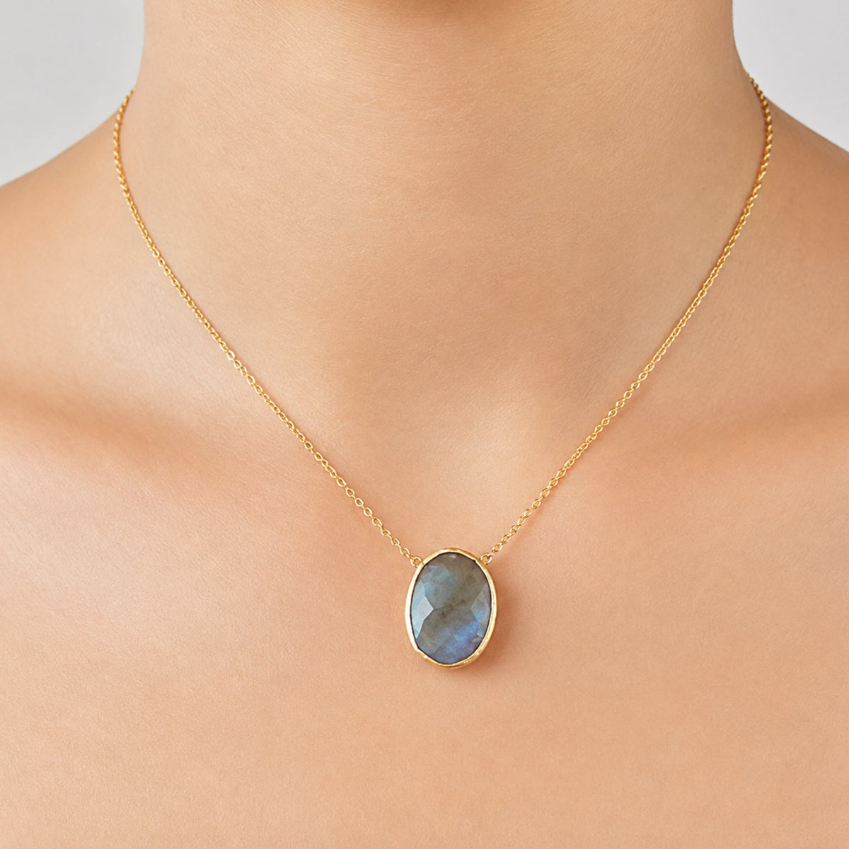 Zoomed in image of minimal gold chain faceted labradorite pendant necklace on models neck