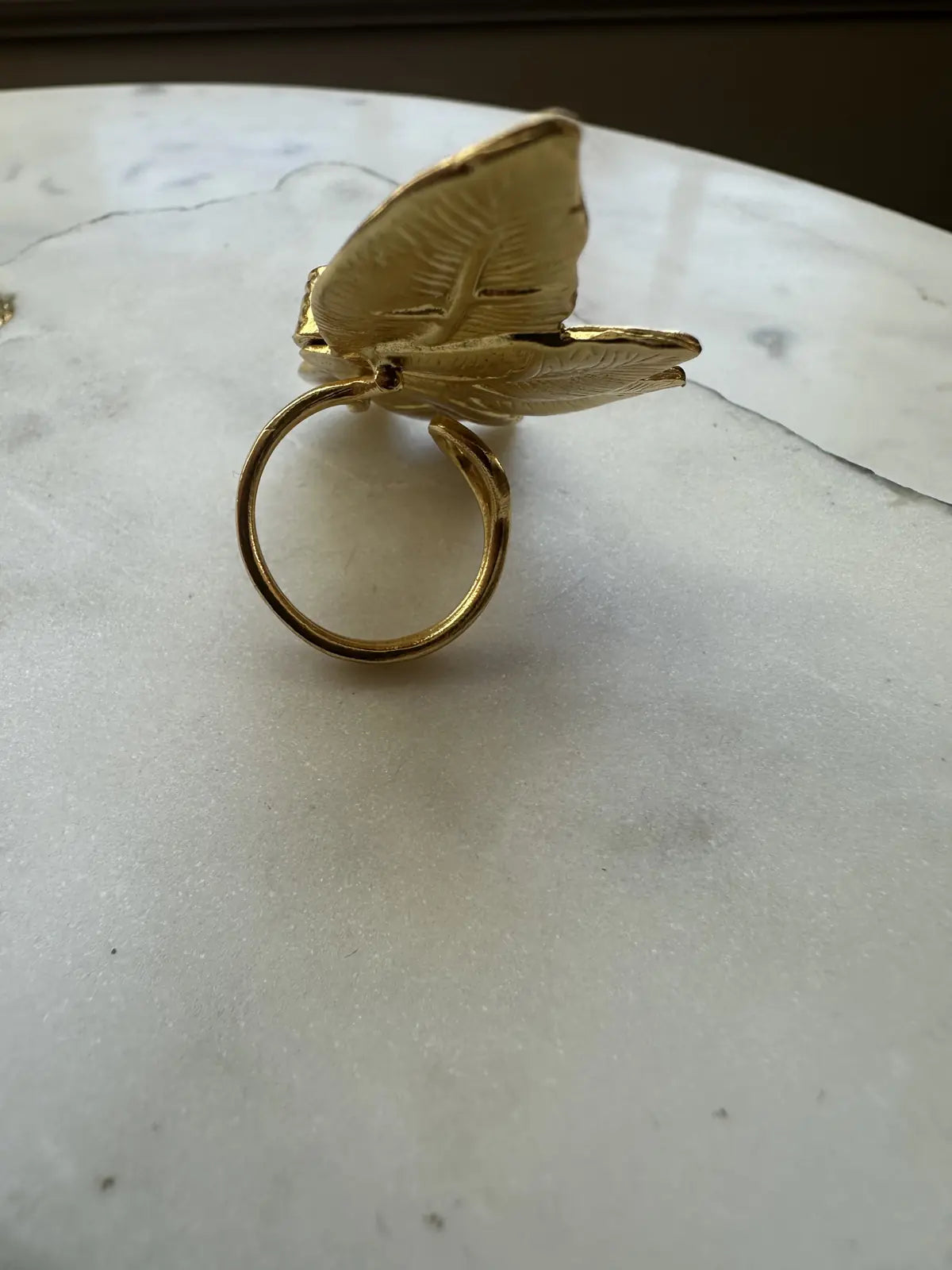 Back of Gold flower ring on a marble surface