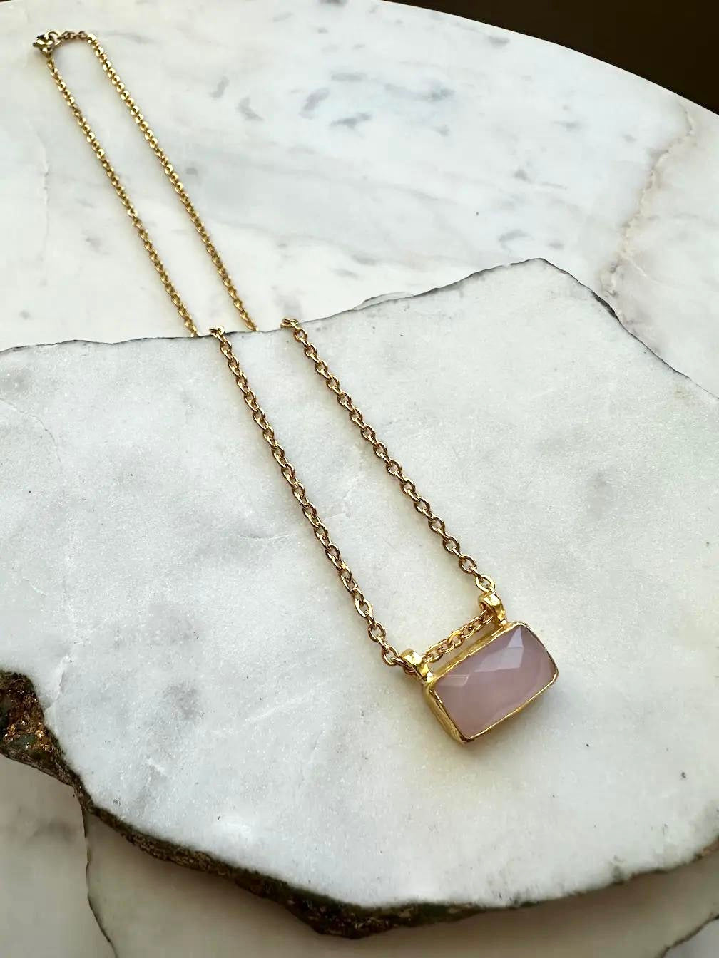 Handmade Necklace with a 21 karat gold-plated pink rose quartz gemstone pendant necklace on a marble surface