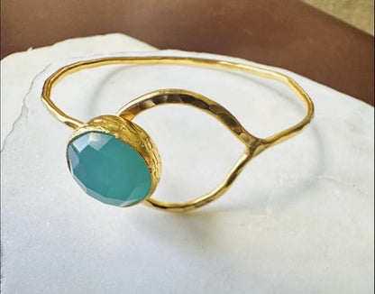 Gold-plated bracelet with a round Aqua chalcedony stone on a white surface
