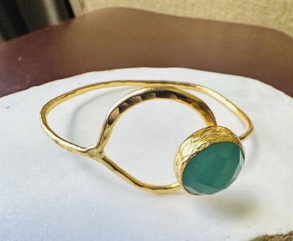 Gold-plates bracelet with aqua chalcedony round stone on a white surface