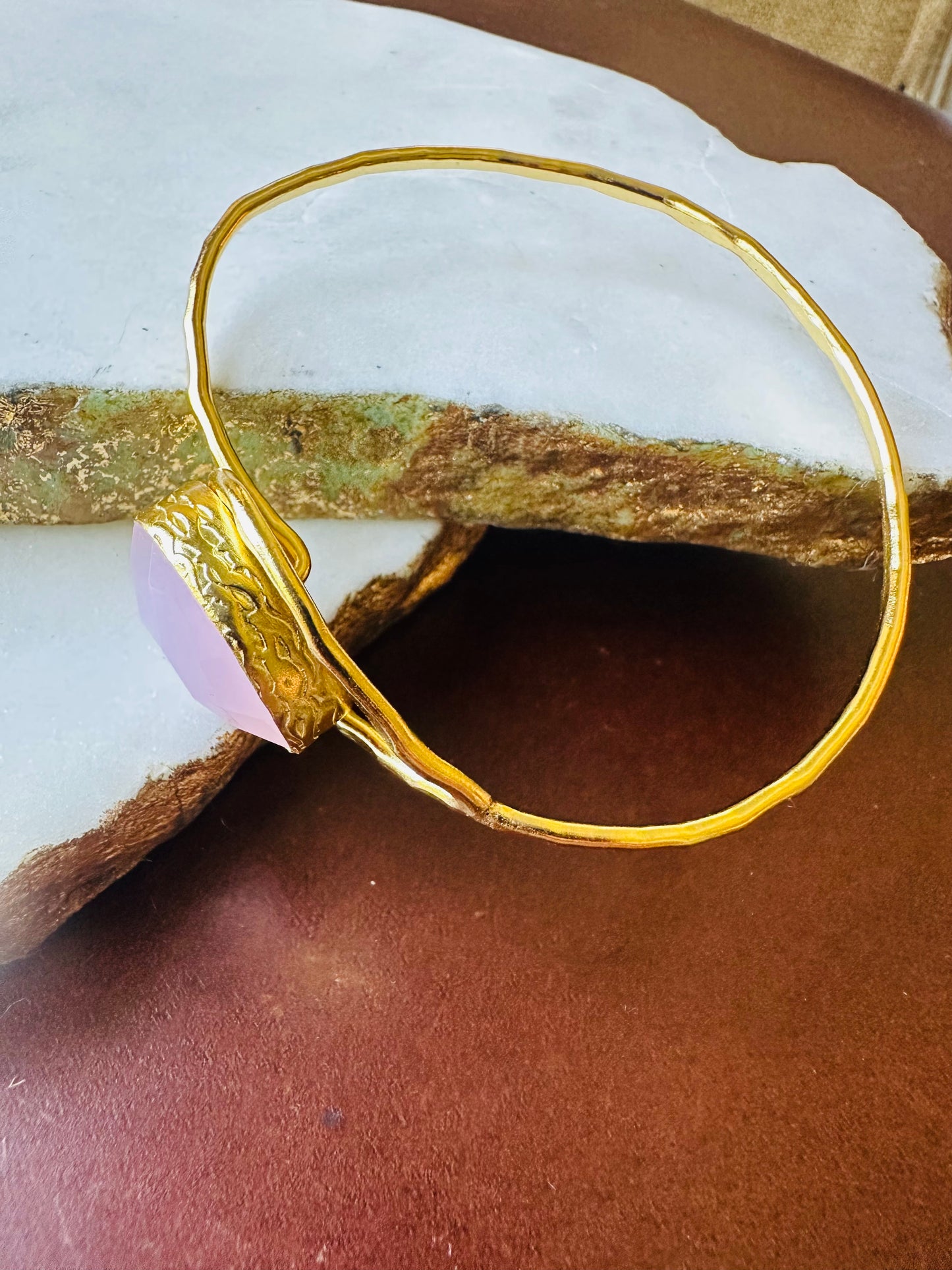 Handmade Gold bracelet with a pink gemstone on a white background-facing-left