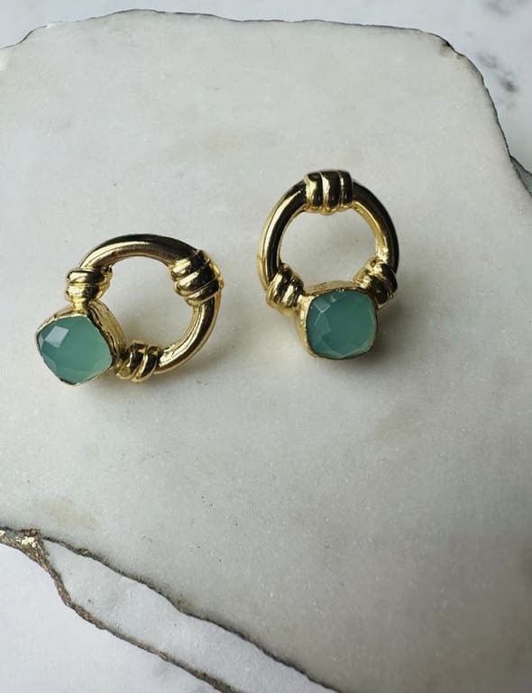 Handcrafted sustainable Gold-plated Aqua Chalcedony doorknocker stud earrings on a marble slabs with one diagonally set