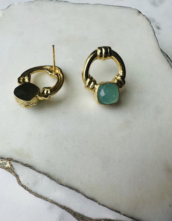 Artisanal eco-friendly Gold-plated doorknocker Aqua chalcedony earrings on a marble surface with one set faced down  