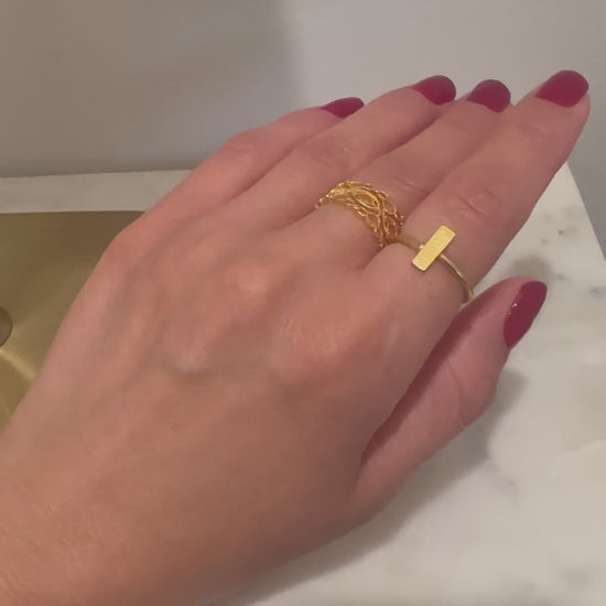 Video of a hand wearing beautiful dainty waterproof 21k gold-plated bracelet with rectangle in center and matching ring on index finger. The middle finger has a gold-plated lace designed band. The Bebek Jewels jewelry is waterproof.