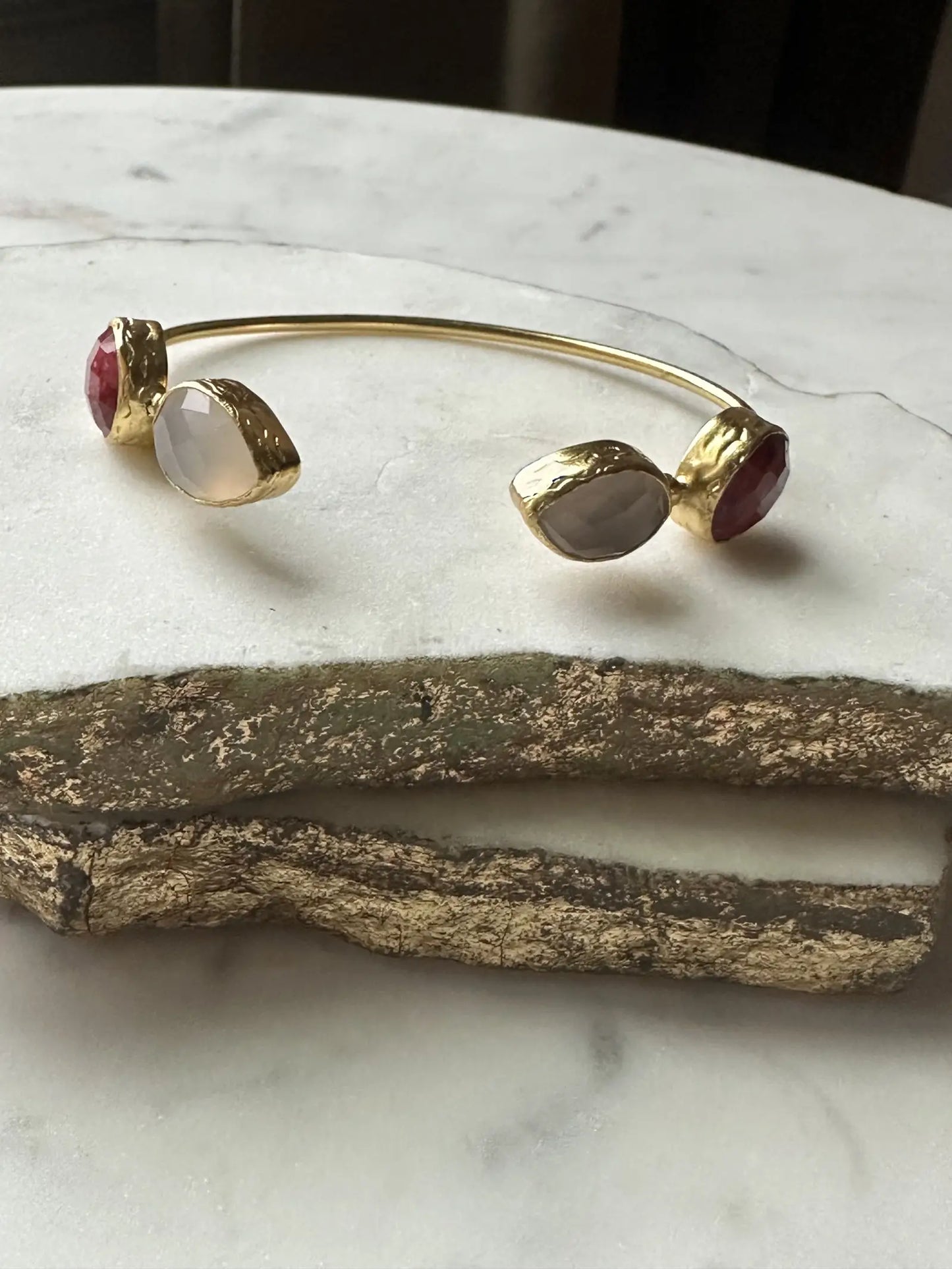 Gold-plated handmade ruby bracelet with gemstones on a marble surface