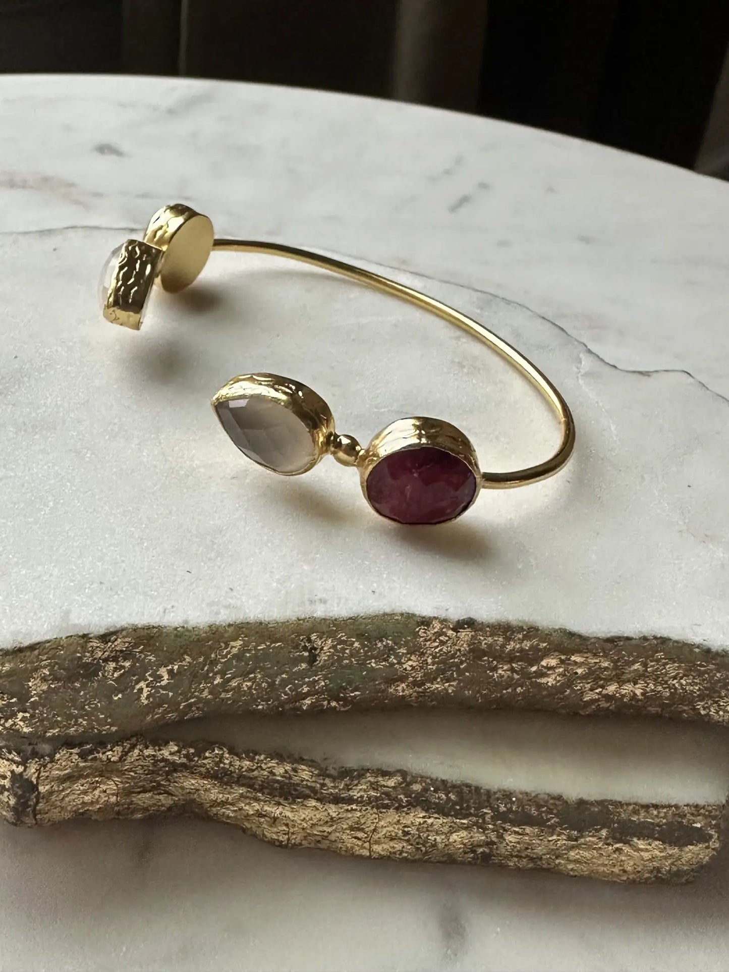 Gold-plated semi-fine gemstone bracelet with rubies on a marble surface