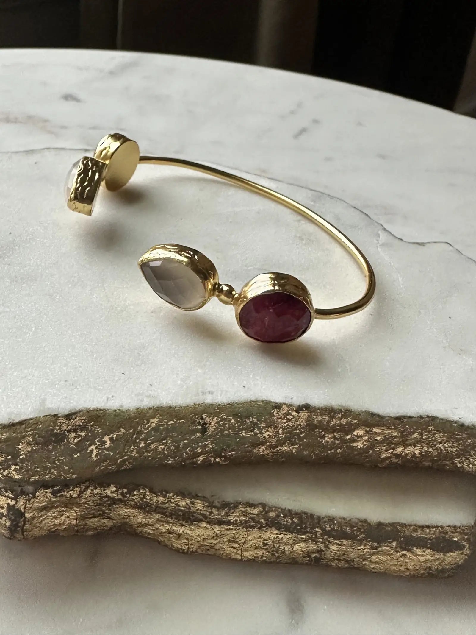 Gold-plated semi-fine gemstone bracelet with rubies on a marble surface