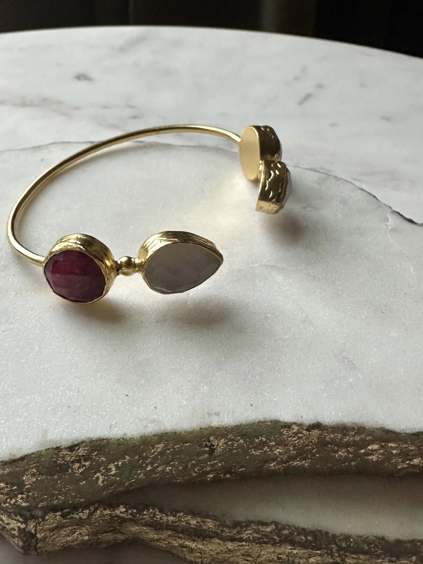 Gold-plated sustainable gemstone bracelet with ruby on a marble surface
