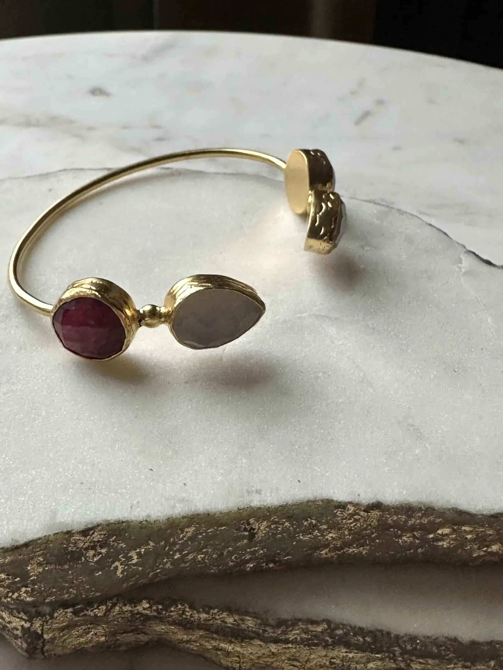 Gold-plated sustainable gemstone bracelet with ruby on a marble surface